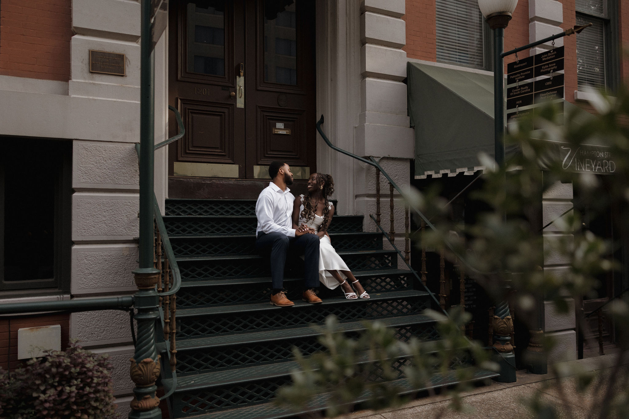 A couple shares a private moment sitting on the stairs of a Main Street Columbia, South Carolina business during their engagement photography session.