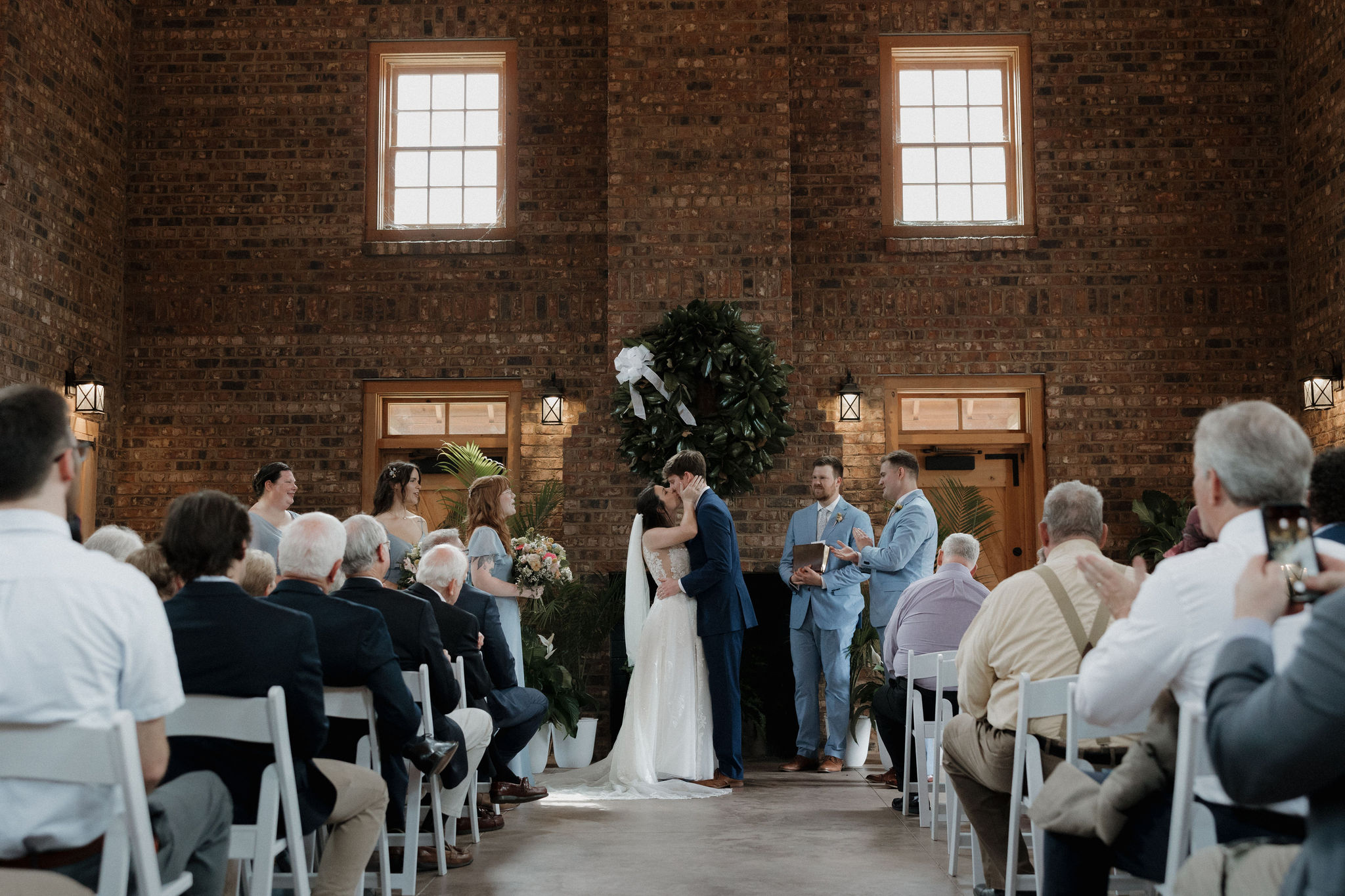 A bride & groom share their first kiss during their indoor wedding ceremony at The Revolutionary War Visitor Center in Camden, South Carolina.