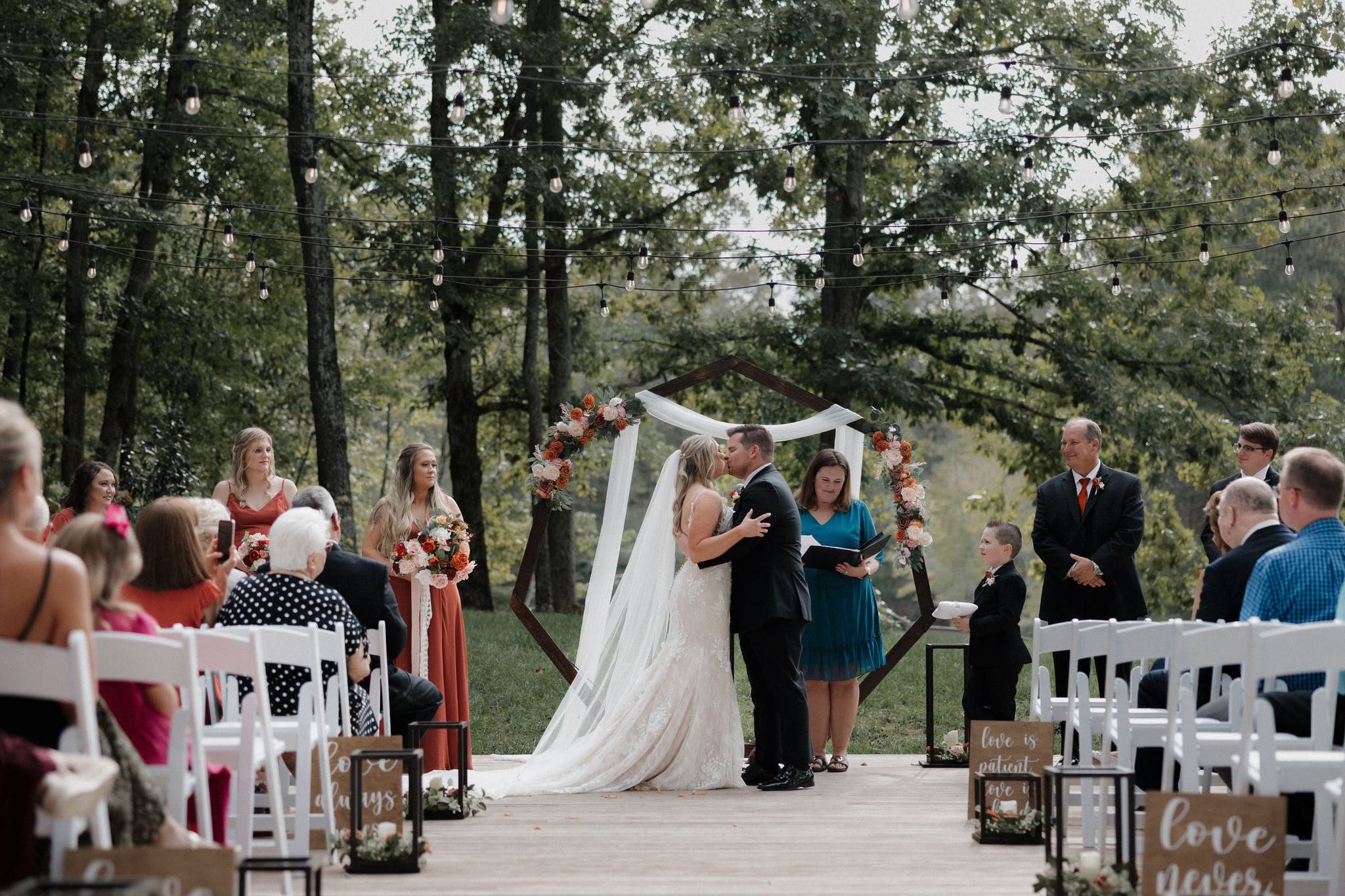 A couple shares their first kiss during their backlit wedding ceremony at Piney Grove Ranch in Gray Court, SC.
