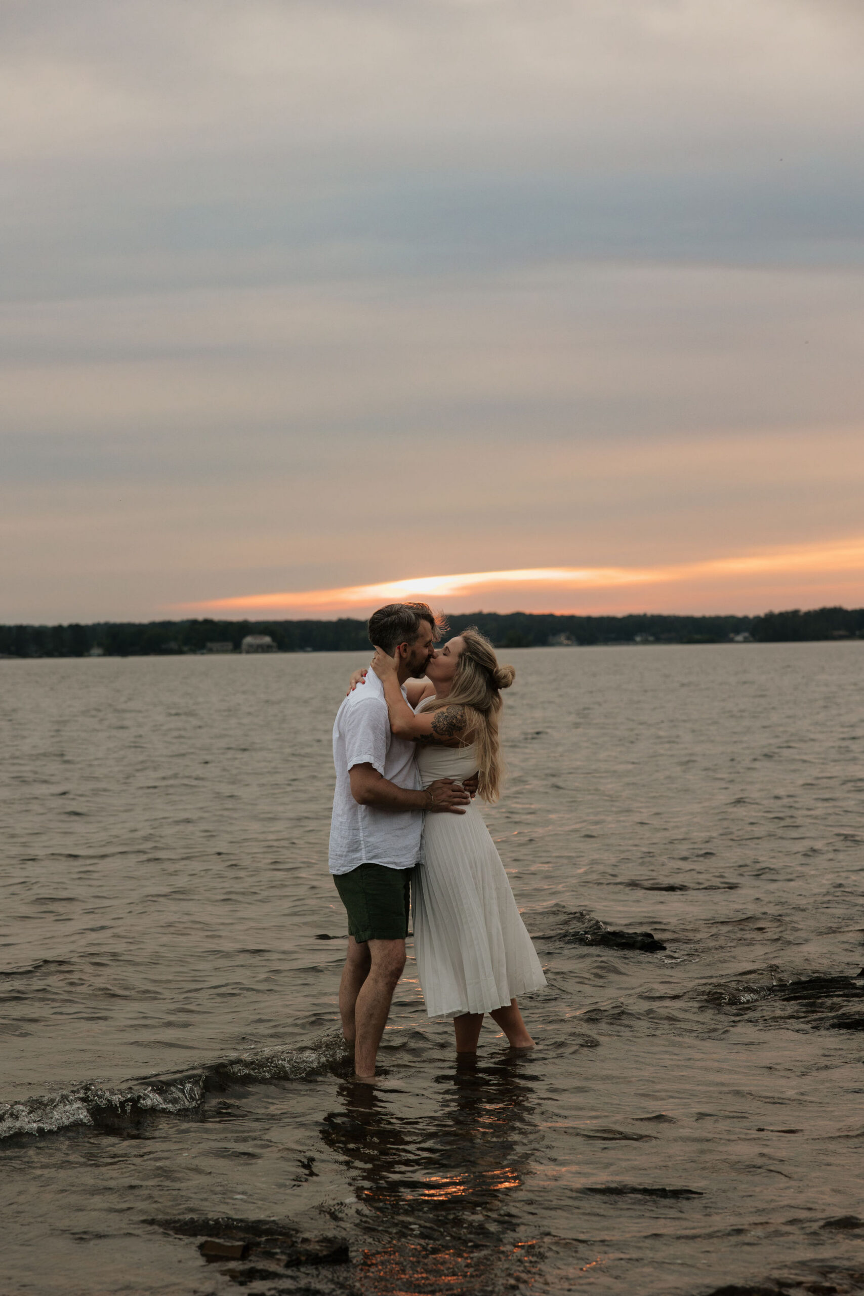 Kelly and Philip share a kiss in the water during their lakeside storytelling engagement session in South Carolina.