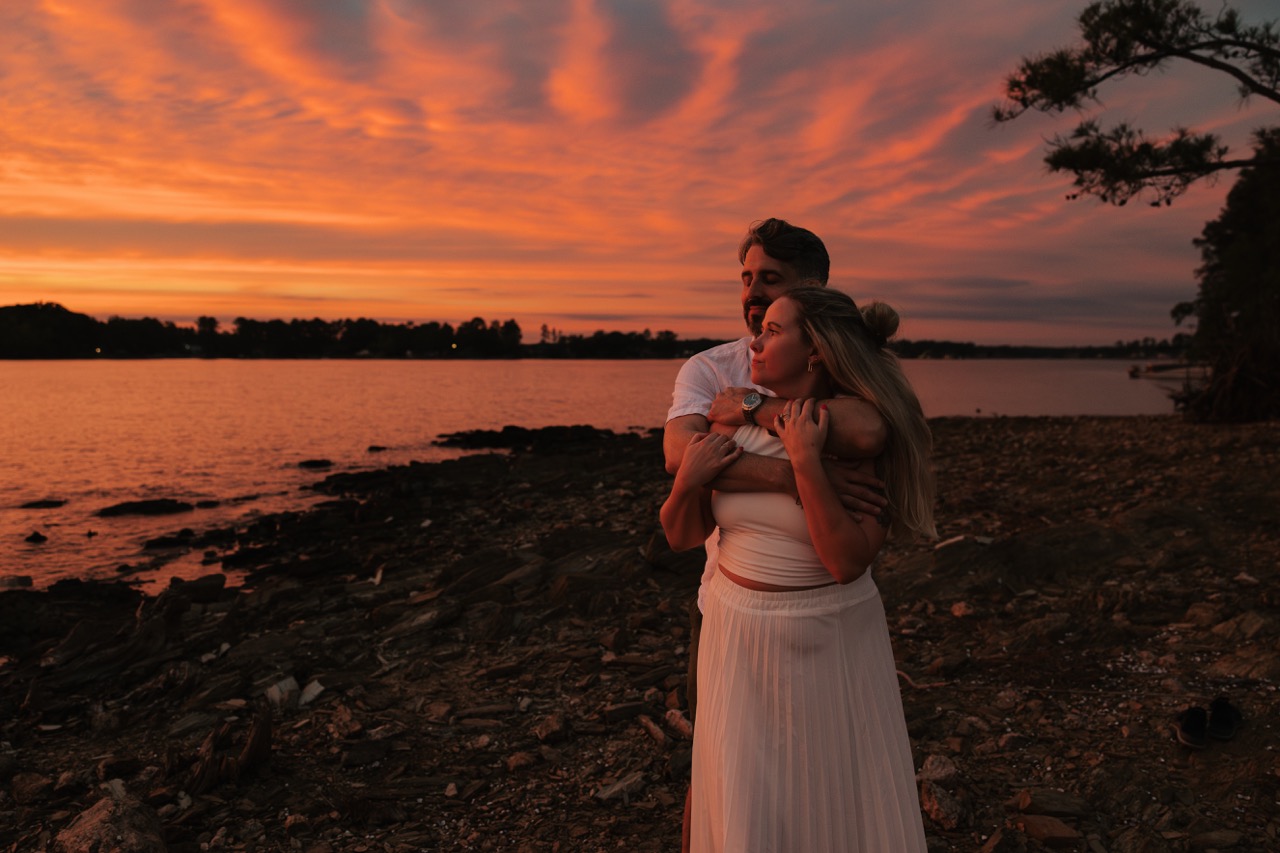 A couple shares an embrace at the lake near Columbia South Carolina as they look off into the sunset.